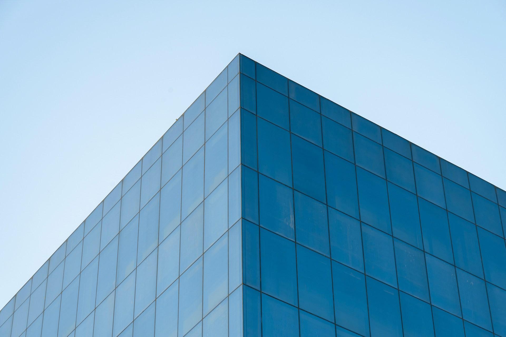 Fachada de vidrio azul de un edificio moderno contra el cielo